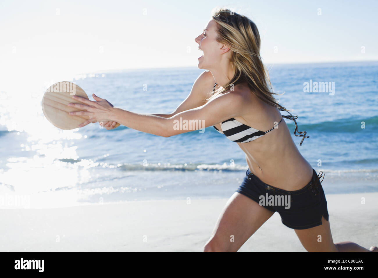 Donna che gioca a tennis in spiaggia Foto Stock