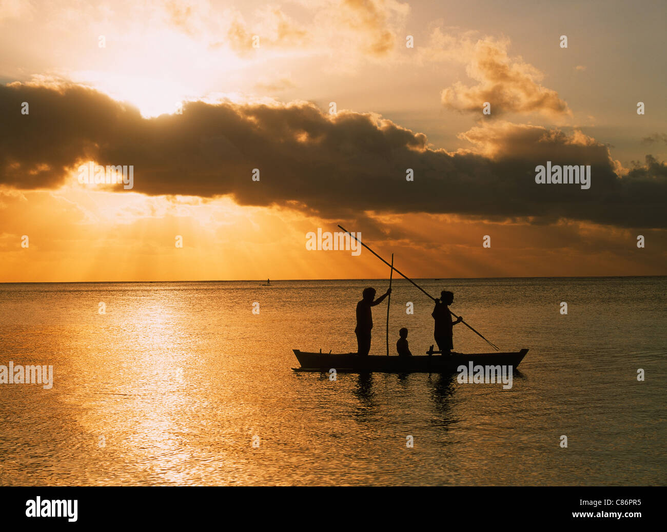 La famiglia in canoa outrigger pesca subacquea sull'isola di Aitutaki Lagoon in Isole Cook al tramonto Foto Stock