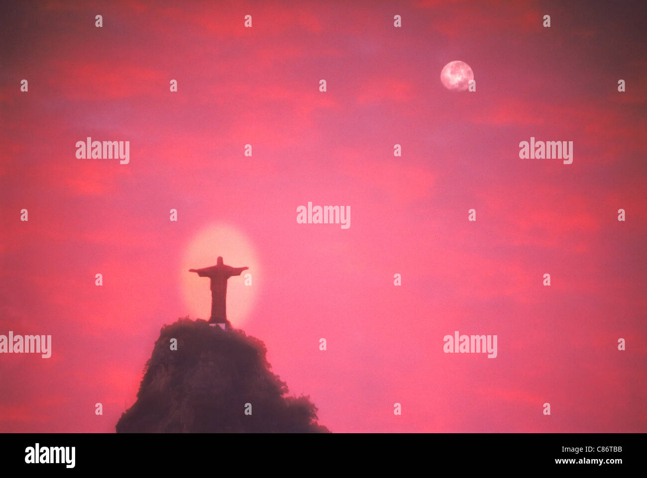 Il Cristo del Corcovado cercando su Rio de Janeiro sotto la luna piena e passaggio di nuvole al tramonto Foto Stock