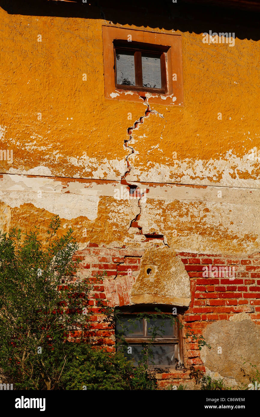 Il vecchio muro di casa con una fessura tra il traino di windows Foto Stock