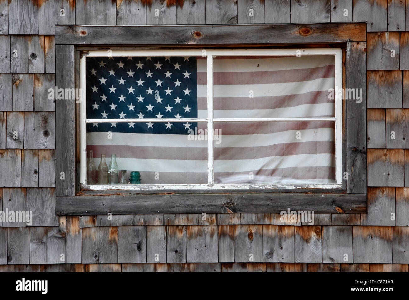 Una bandiera americana nella finestra di un fienile con alterò le assicelle in New Hampshire Foto Stock