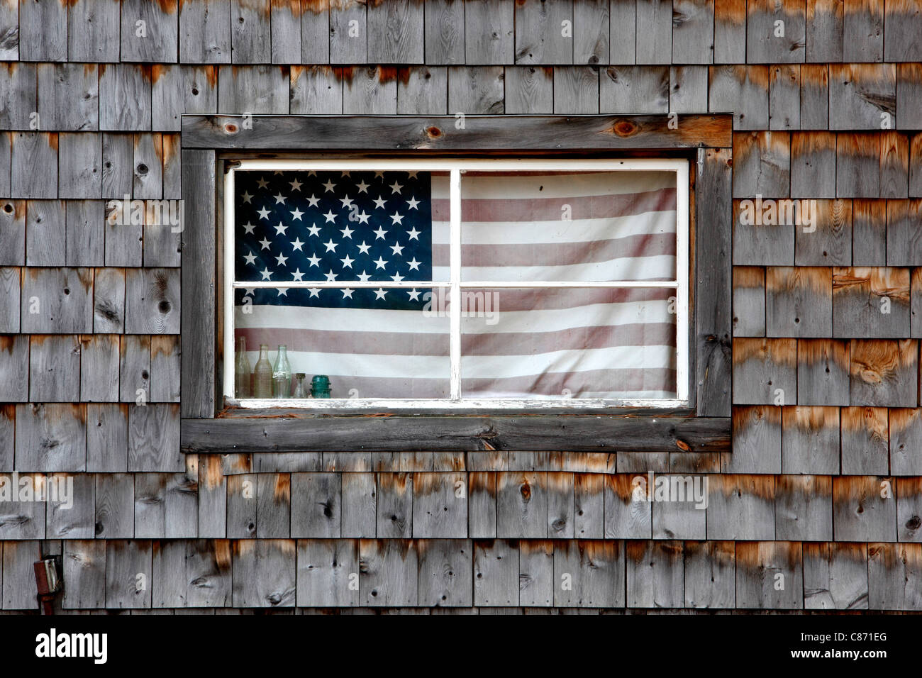 Una bandiera americana nella finestra di un fienile con alterò le assicelle in New Hampshire Foto Stock