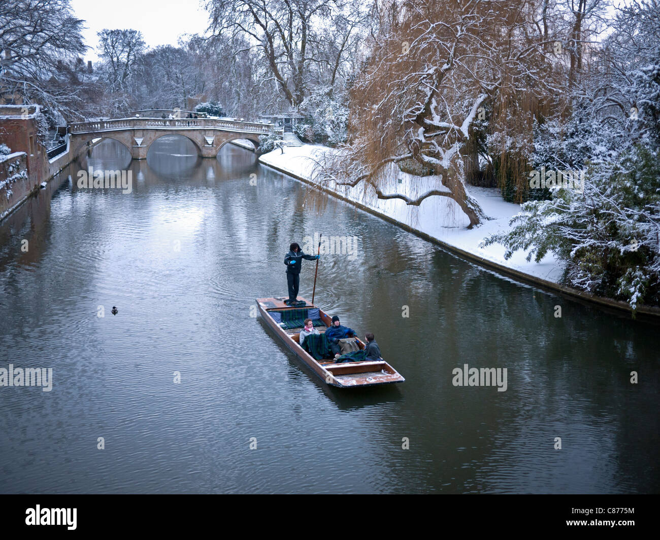 Punting sul fiume Cam alla spalle Cambridge su terreni innevati e congelati al giorno. Clare College bridge in background. Foto Stock