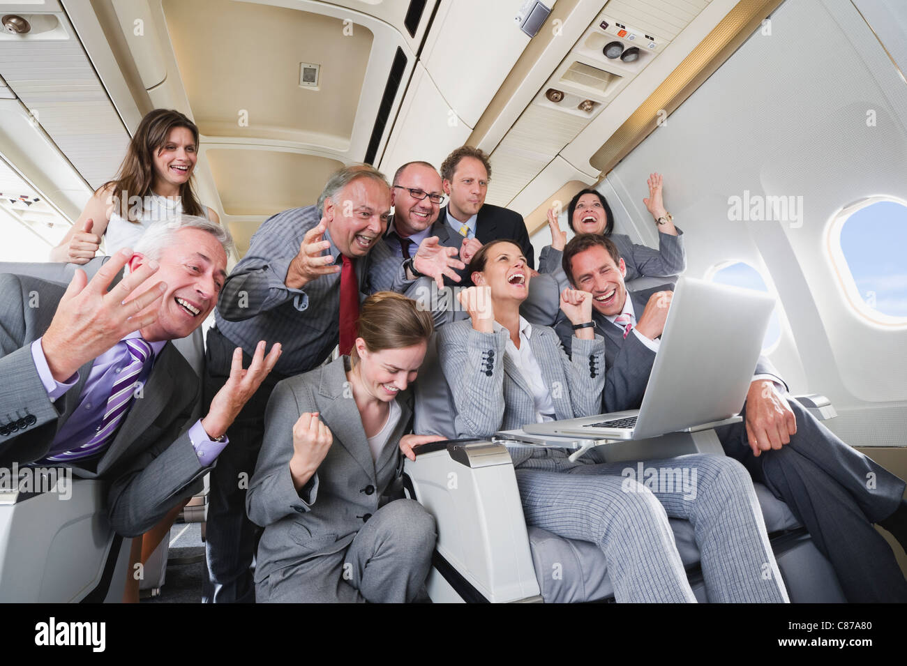 In Germania, in Baviera, Monaco di Baviera, gruppo di viaggiatori alla ricerca di computer portatile in business class cabina aereo, ridendo Foto Stock
