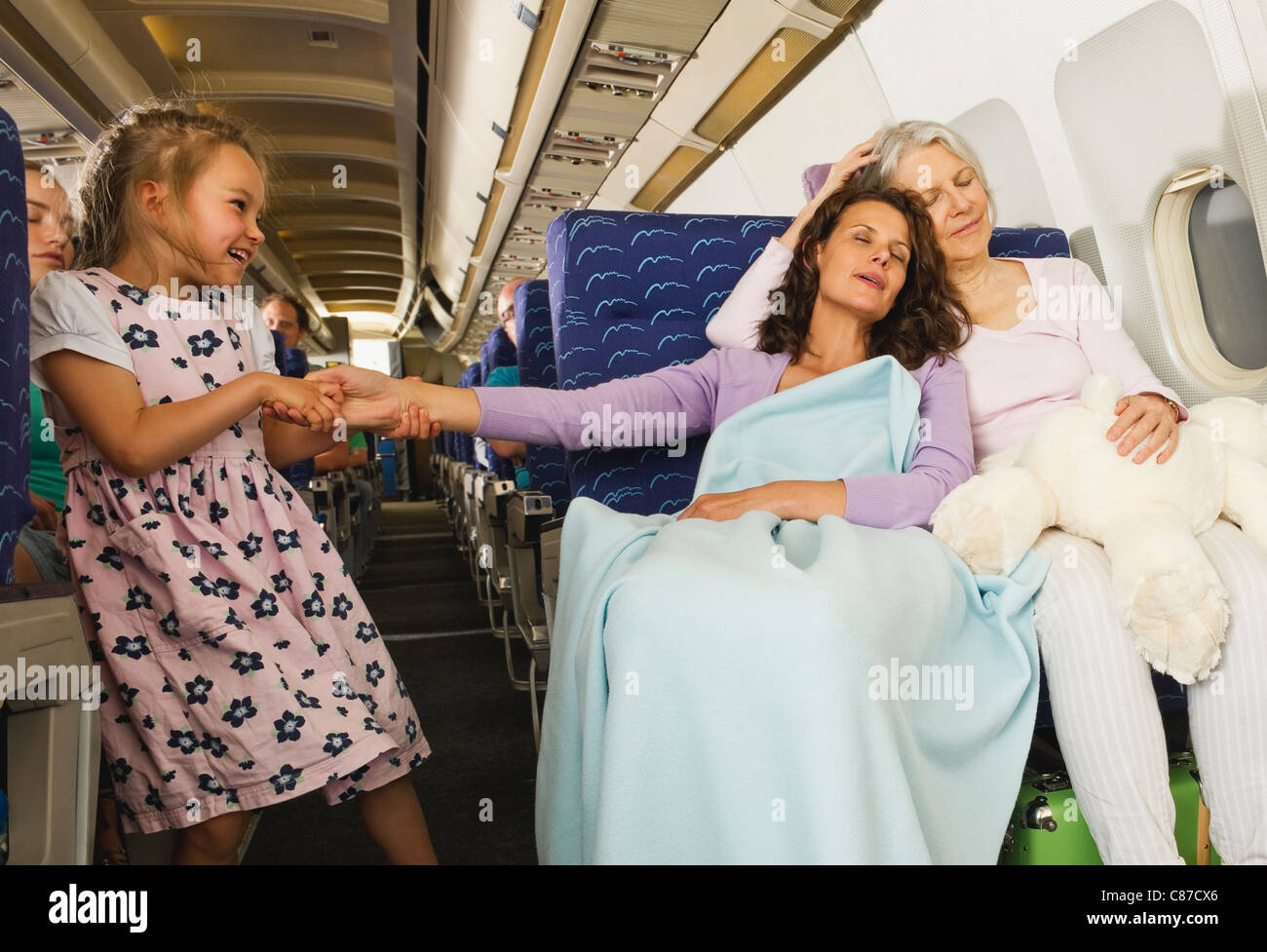 Germania - Monaco di Baviera, donne dormire e ragazza tirando la donna la mano in classe economy aereo di linea Foto Stock