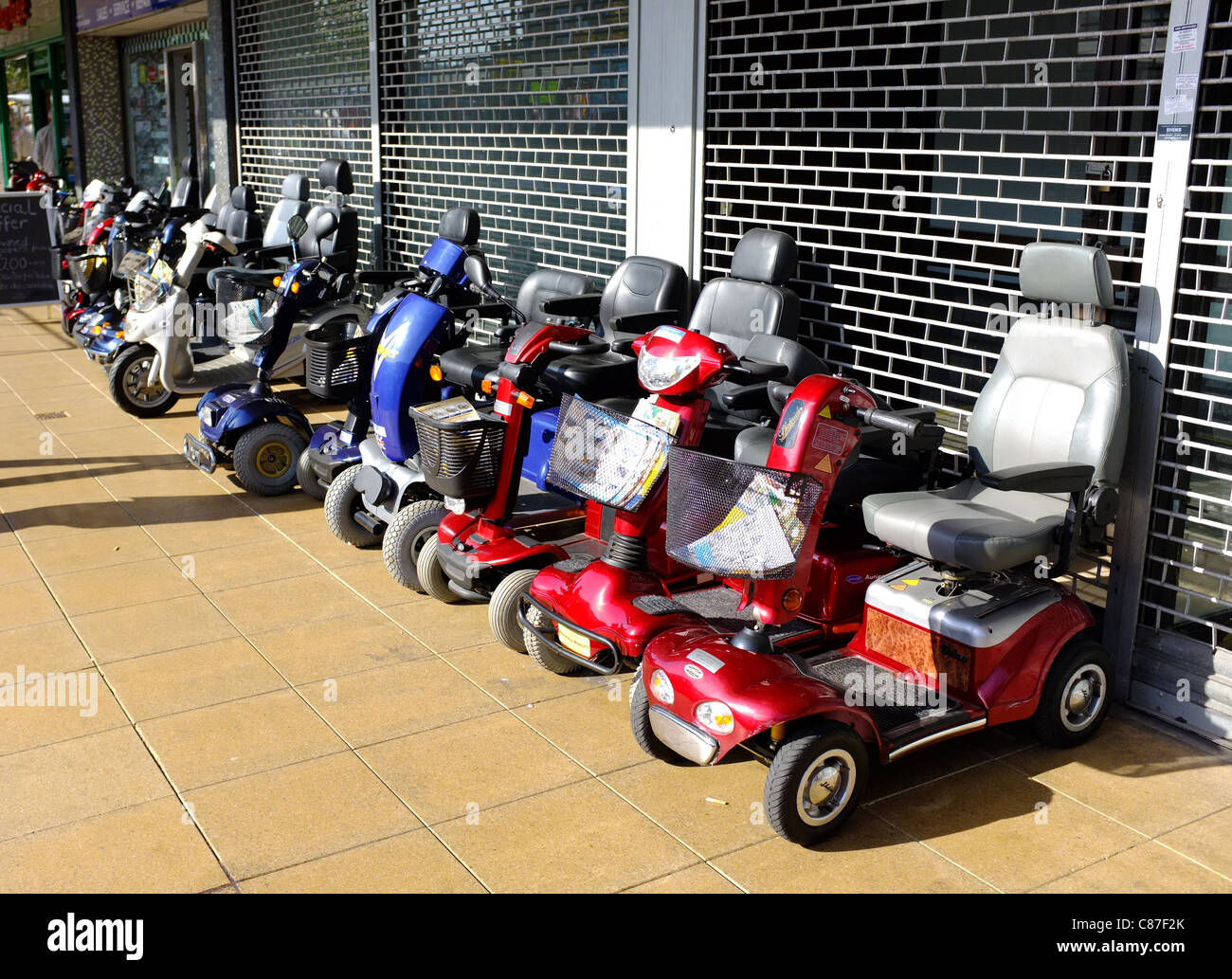 Mobilità scooter schierate al di fuori di un negozio nel mercato di Basildon Foto Stock
