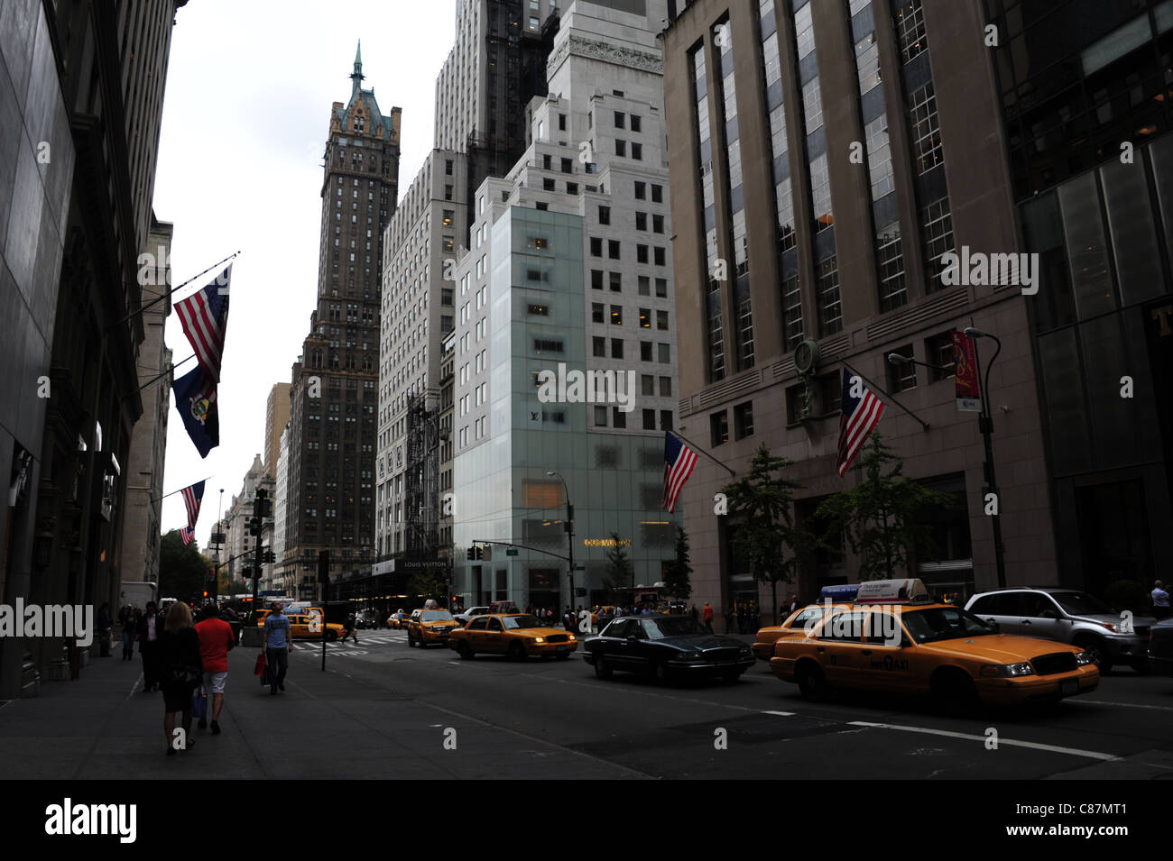 Auto persone giallo taxi bandierine americane Tiffany & Co negozio Louis Vuitton, verso Sherry-Netherland Hotel, la Fifth Avenue, New York Foto Stock