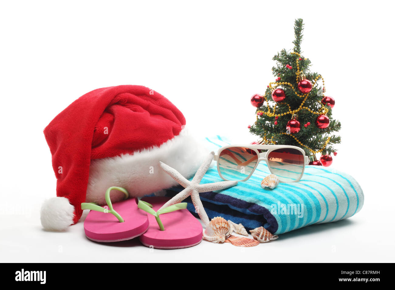 Santa Claus hat e albero di Natale con spiaggia accessori su sfondo bianco. Foto Stock