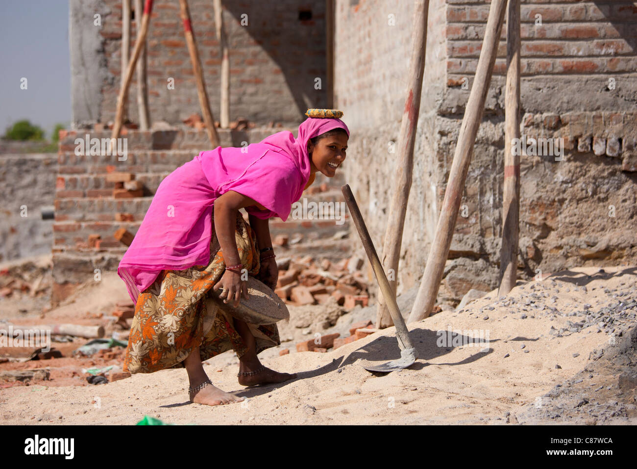 Donna builder cemento porta sul suo capo al villaggio Khore, Rajasthan, India Foto Stock