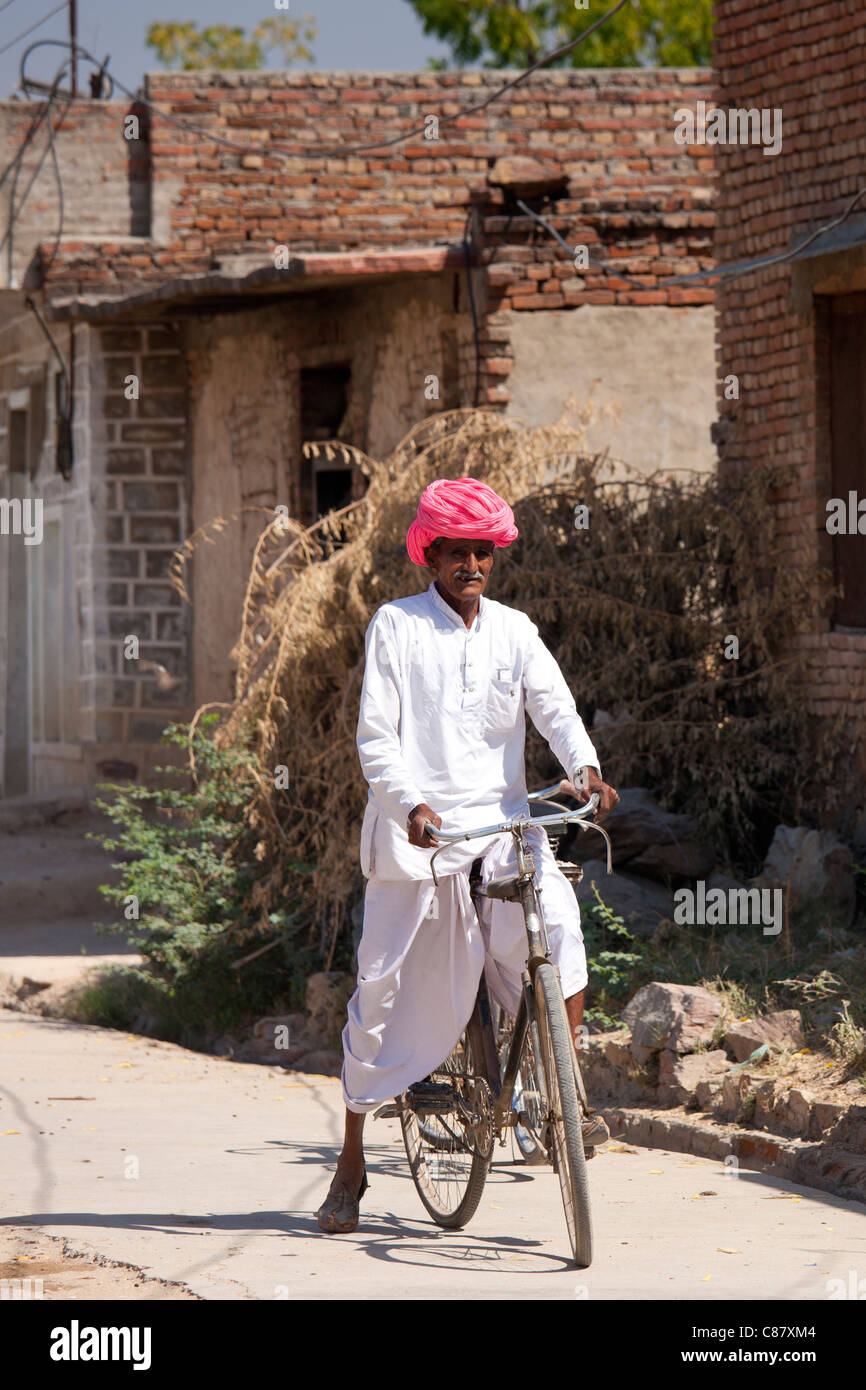 Indian uomo in abbigliamento tradizionale bicicletta equitazione nel villaggio Jawali nel Rajasthan, India settentrionale Foto Stock