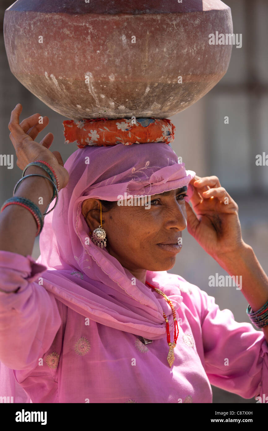 Donna indiana in sari il recupero dei vasi d'acqua dal pozzetto a Jawali villaggio in Rajasthan, India settentrionale Foto Stock