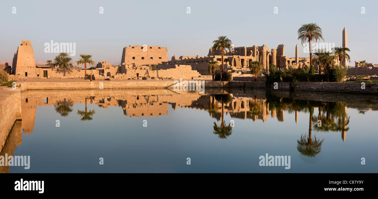 Vista al tramonto sul lago sacro verso i tralicci e Hypostyle Hall presso il Tempio di Karnak, riva orientale del Nilo Luxor Egitto. Foto Stock