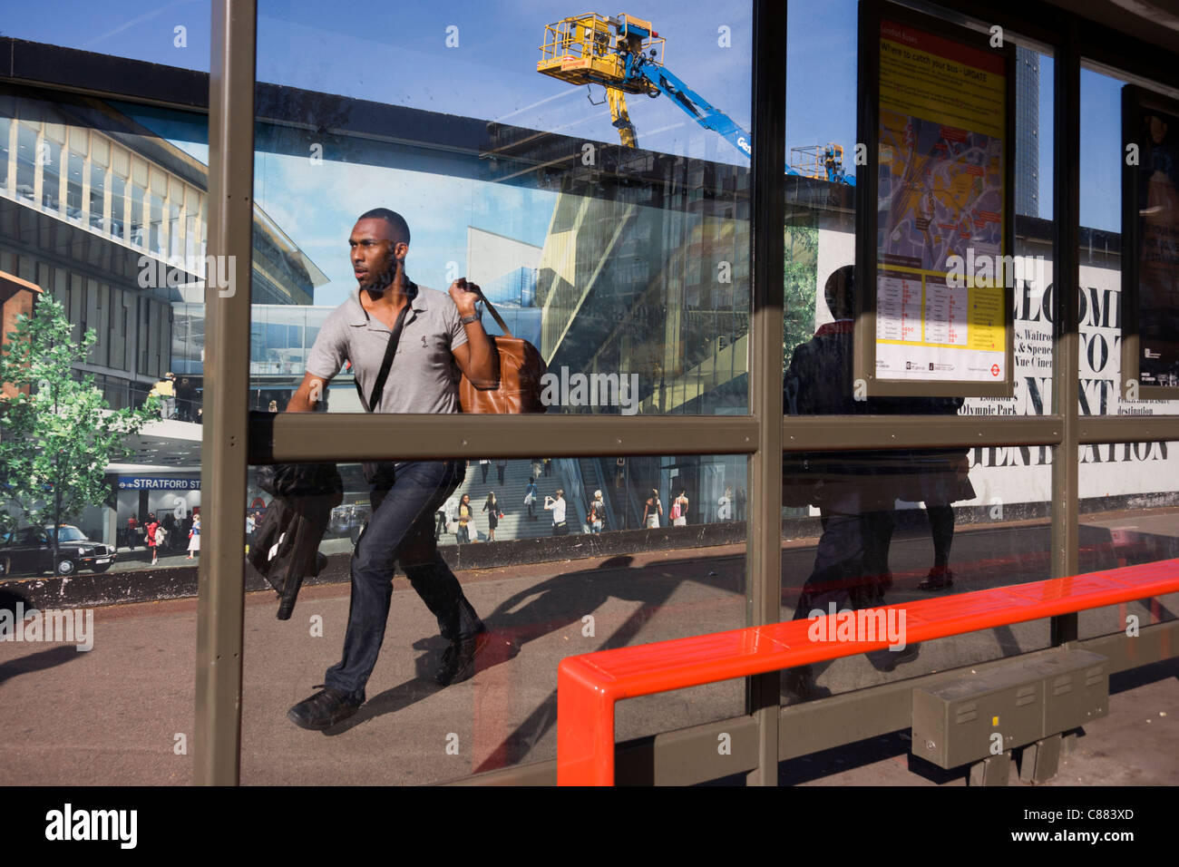 Uomo locale passa una palizzata che mostra l'aspirazione e il consumismo della vicina città di Westfield Shopping Complex, Stratford Foto Stock