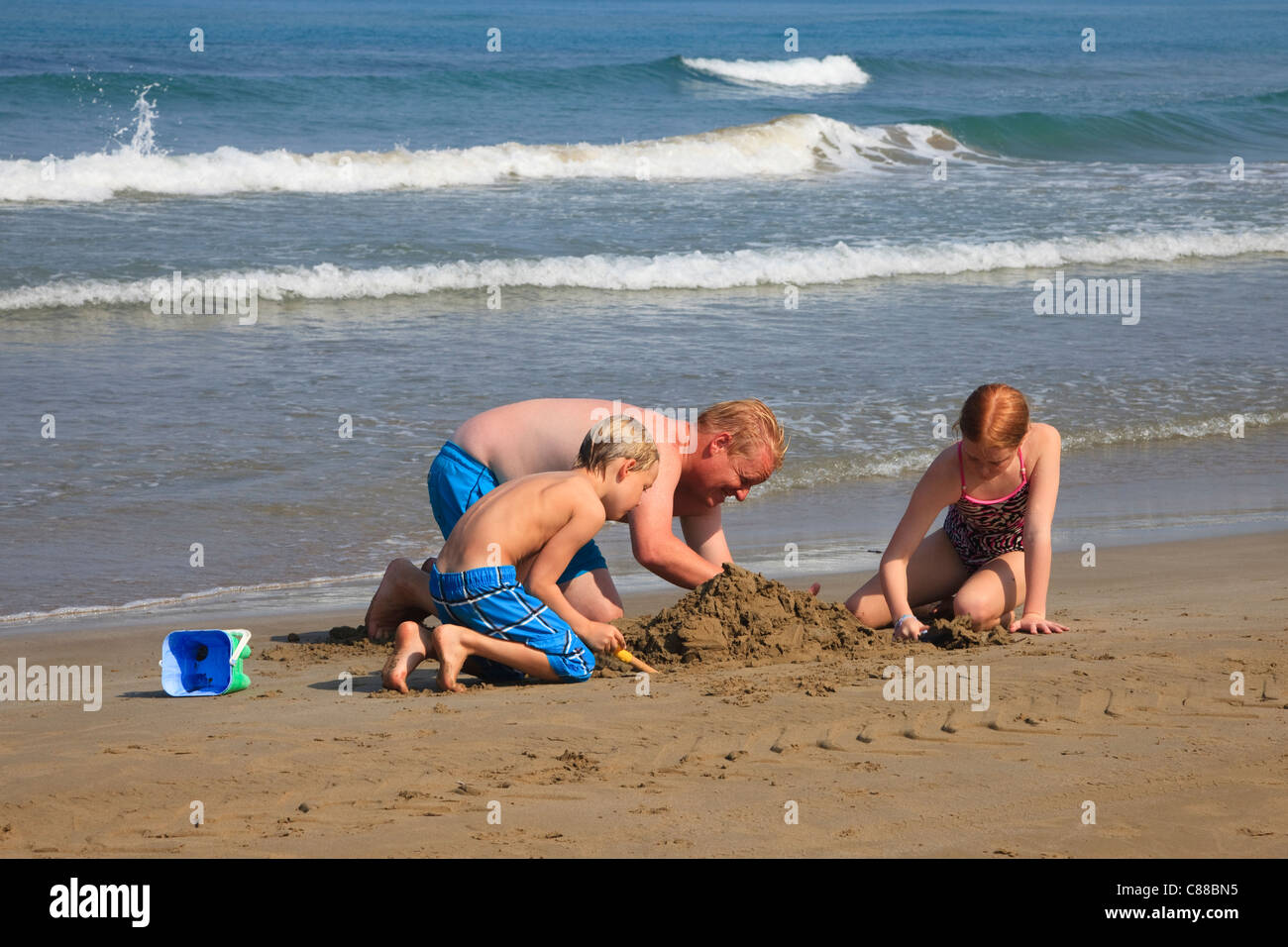 Il padre, il figlio e la figlia per costruire castelli di sabbia sulla spiaggia di Sidari, Corfù, Grecia Foto Stock