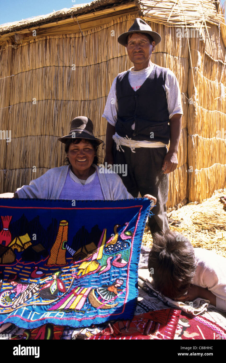 Il lago Titicaca, Perù. L uomo e la donna che mostra souvenir Panni ricamati sull'isola galleggiante di Uros. Foto Stock
