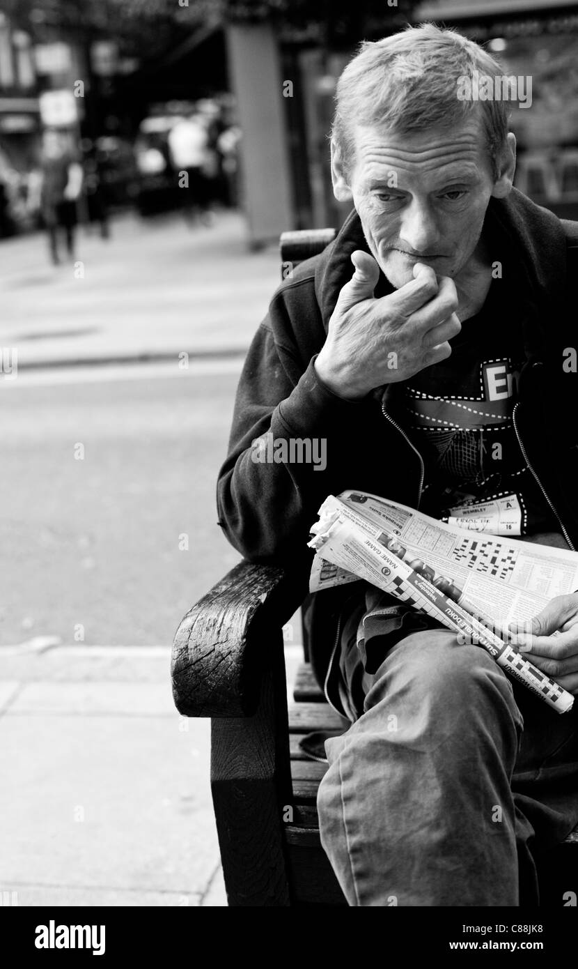 Ritratto in bianco e nero di un senzatetto uomo seduto su una panchina di Londra, Inghilterra, Regno Unito Foto Stock