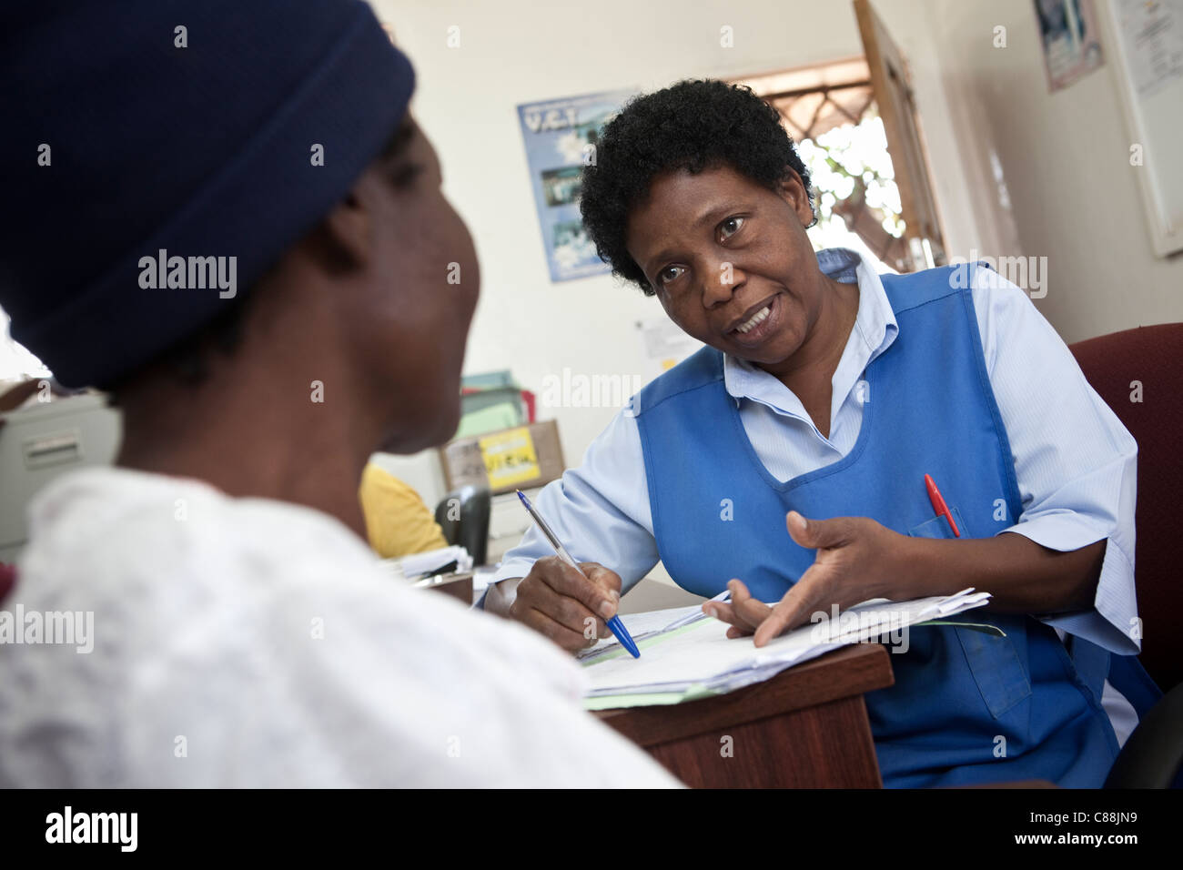 Un infermiere si consulta con un HIV positivo nel paziente un AIDS sollievo clinica supportata da Catholic Relief Services a Kitwe, Zambia. Foto Stock