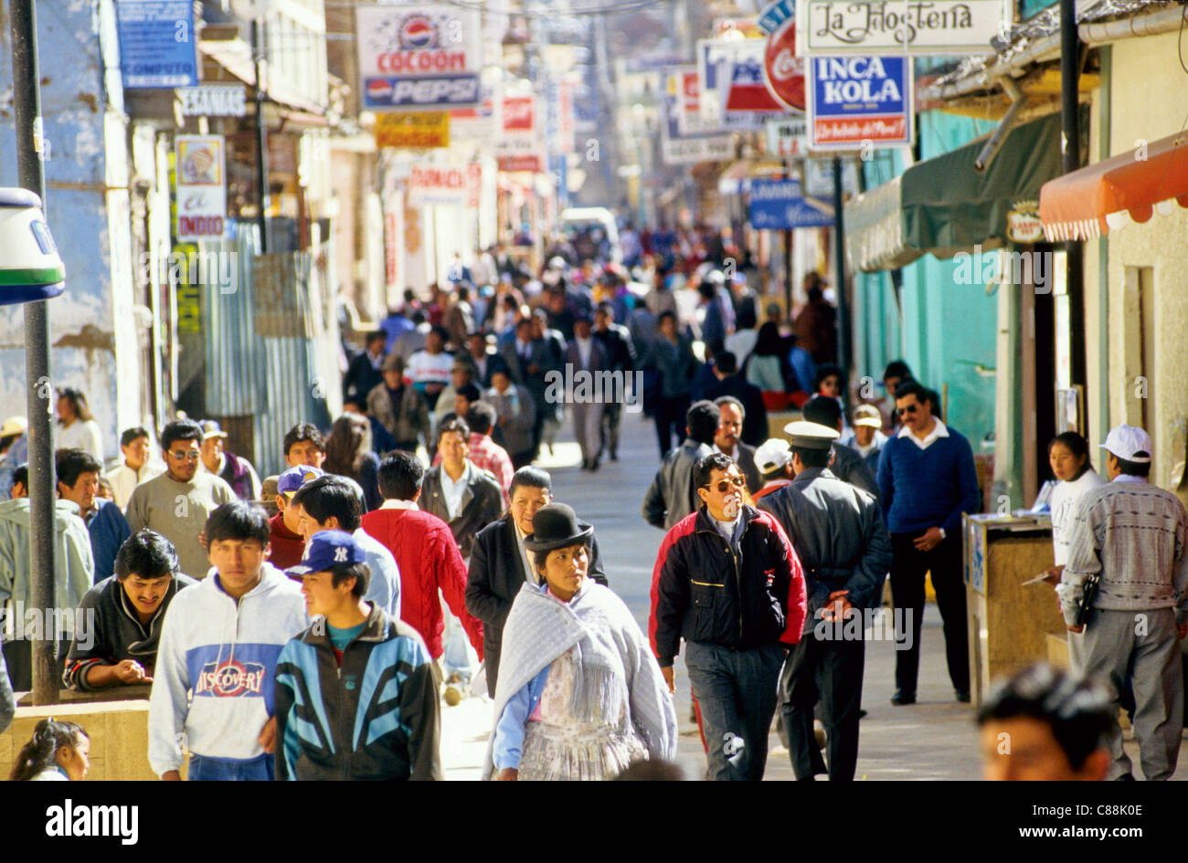 Puno, Perù. Gli uomini e le donne indossando il tradizionale e il moderno vestiti su una strada molto trafficata; molte insegne; poliziotto. Foto Stock