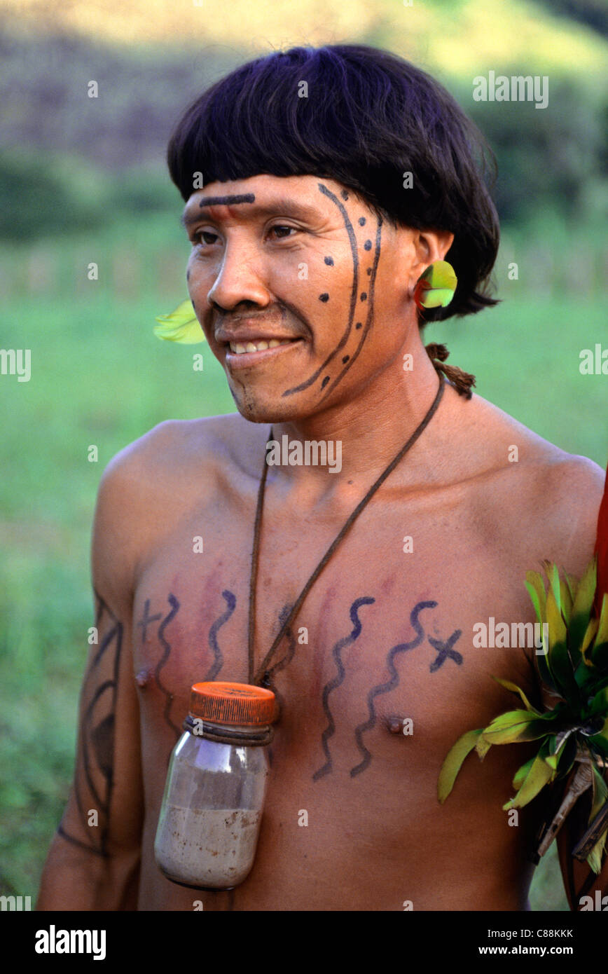 Roraima, Brasile. Prelievo, uno sciamano Yanomami con il suo vaso di tabacco da fiuto allucinogene, viso e corpo di vernice e di decorazioni di piume. Foto Stock