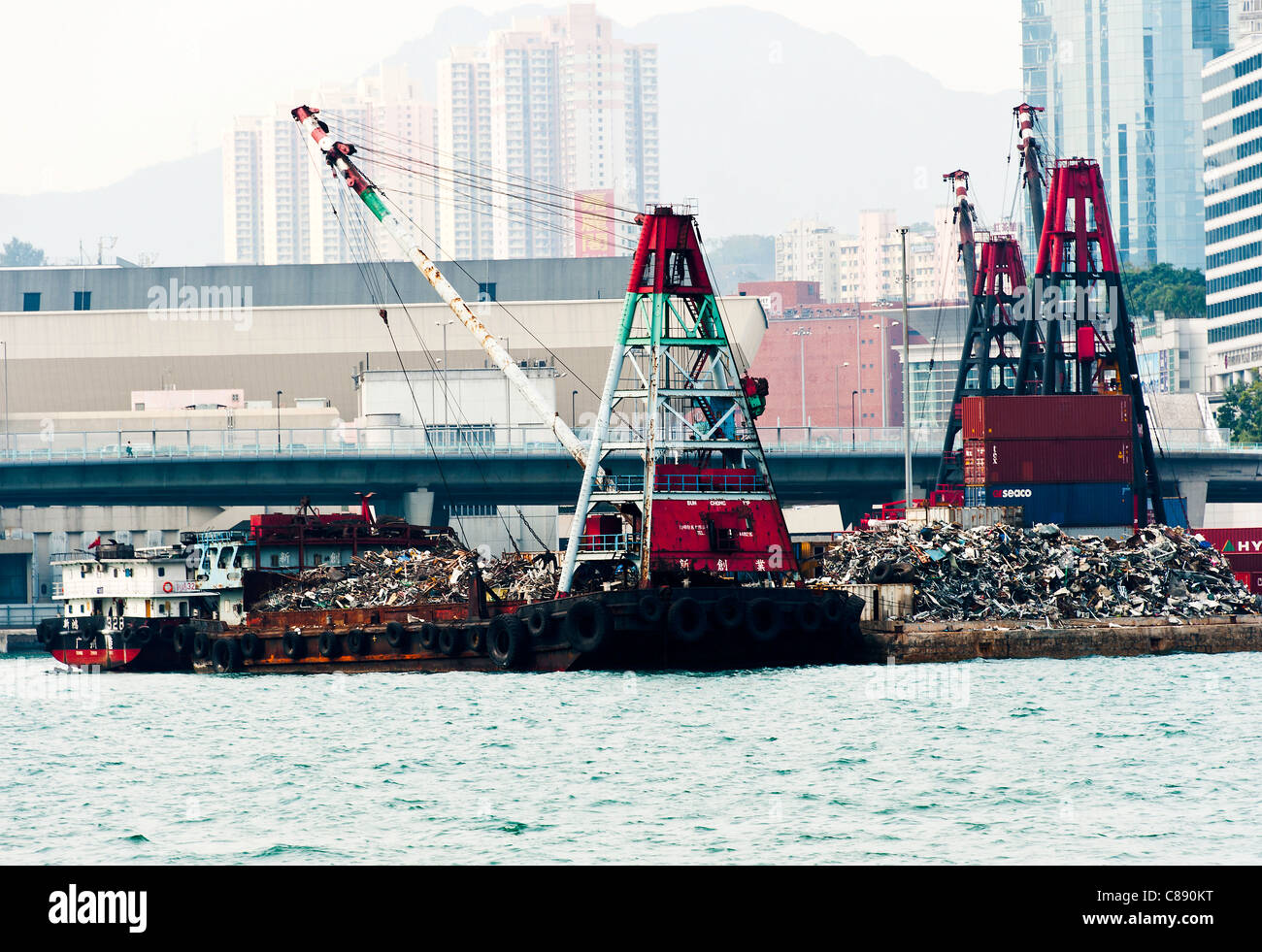 Rottami di metallo in fase di elaborazione su Pier con la chiatta caricato con grande Gru nel porto Victoria Kowloon Hong Kong Cina Asia Foto Stock