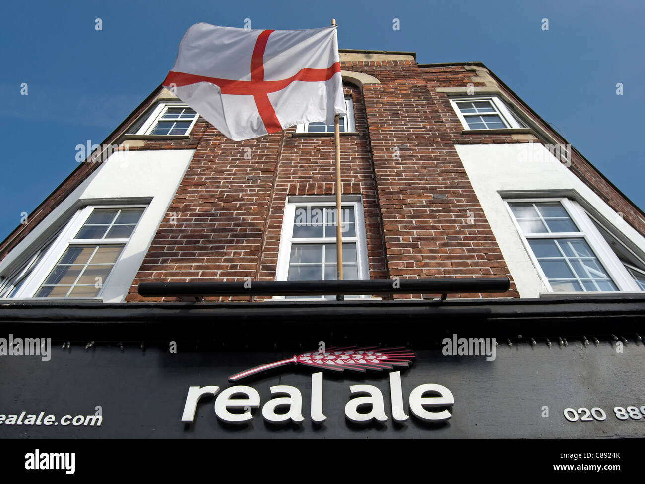 Bandiera di st George al di sopra di un vero e proprio negozio di ale, vendita di birre da british microbirrerie, east twickenham, middlesex, Inghilterra Foto Stock