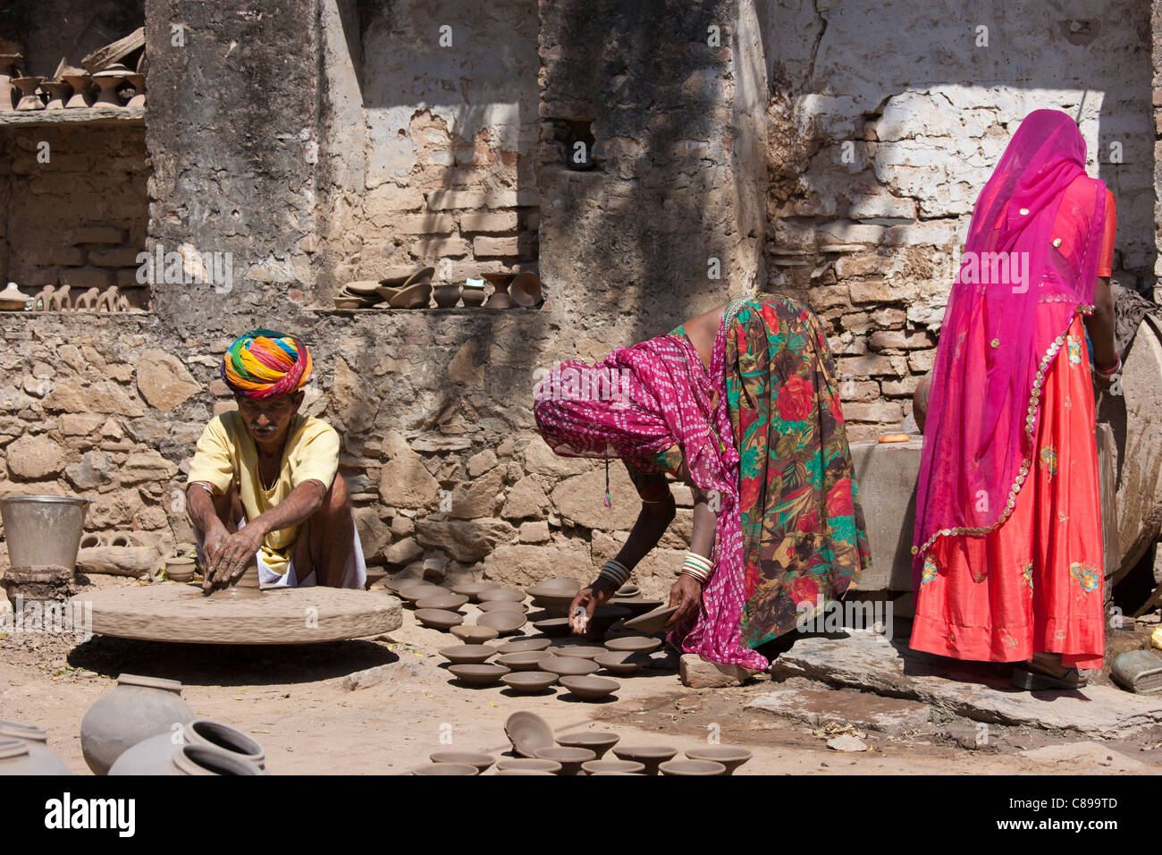 Potter nel tradizionale turbante di Rajasthani lavora a casa con la sua famiglia facendo pentole di creta in Nimaj village, Rajasthan, India Foto Stock