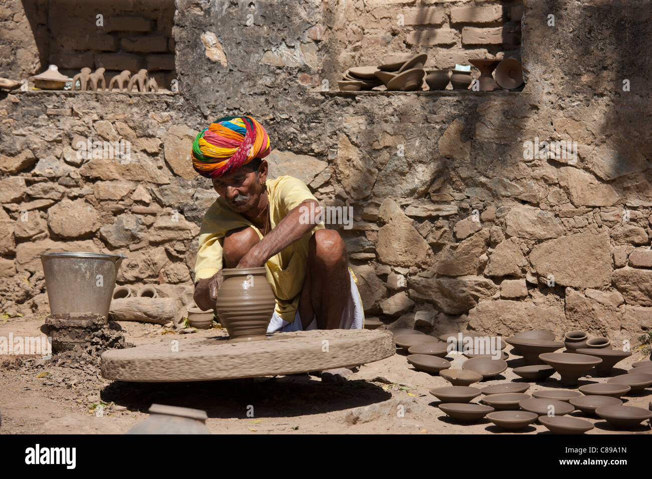 Potter nel tradizionale turbante di Rajasthani opere sul tornio del vasaio a casa rendendo pentole di creta in Nimaj village, Rajasthan, India Foto Stock