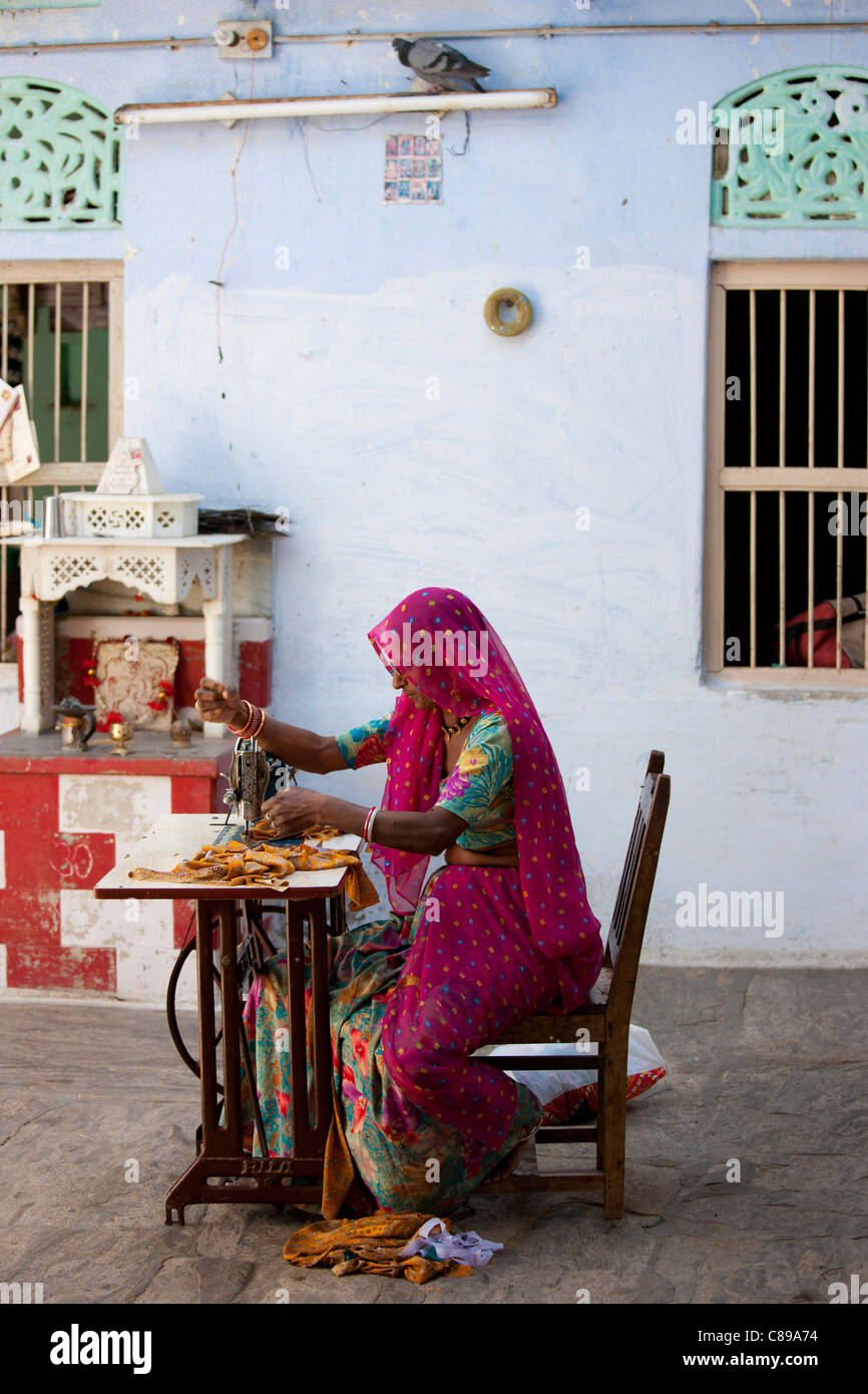 Indian lavoratore a casa la donna nel tradizionale sari di Rajasthani funziona macchina da cucire nel villaggio di Nimaj, Rajasthan, India Foto Stock
