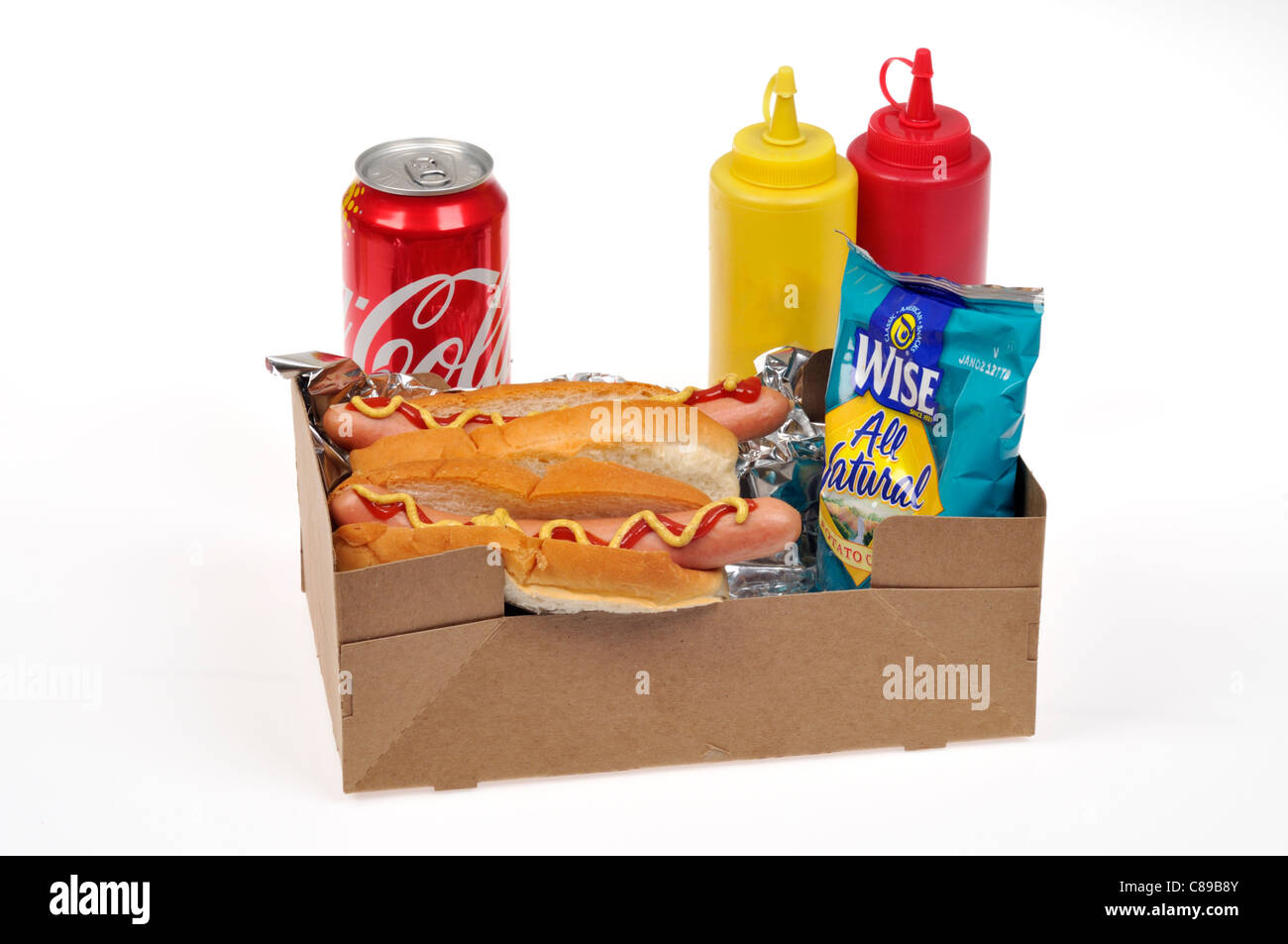 2 hotdog, sacchetto di patatine e una coca cola in un take away vassoio con mostarda e ketchup condimenti su sfondo bianco. Foto Stock