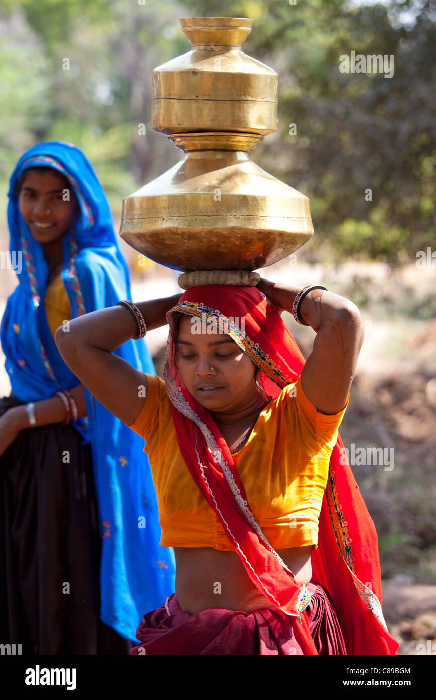 Donna indiana portando vasi d'acqua sul suo capo a Sawai Madhopur nel Rajasthan, India settentrionale Foto Stock