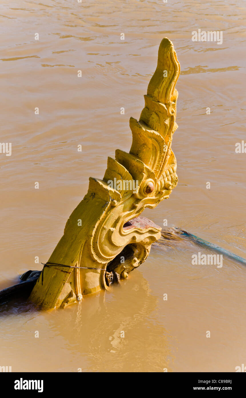 Dragon (naga) scultura in sole parzialmente sommerso dal fango di acqua alta del fiume Ping vicino a Chiang Mai Thailandia Foto Stock