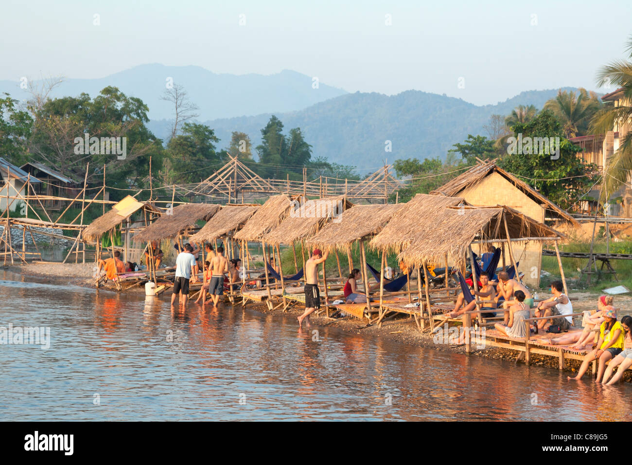 I turisti rilassarsi presso il Nam Song river al tramonto in Vang Vieng, Laos Foto Stock