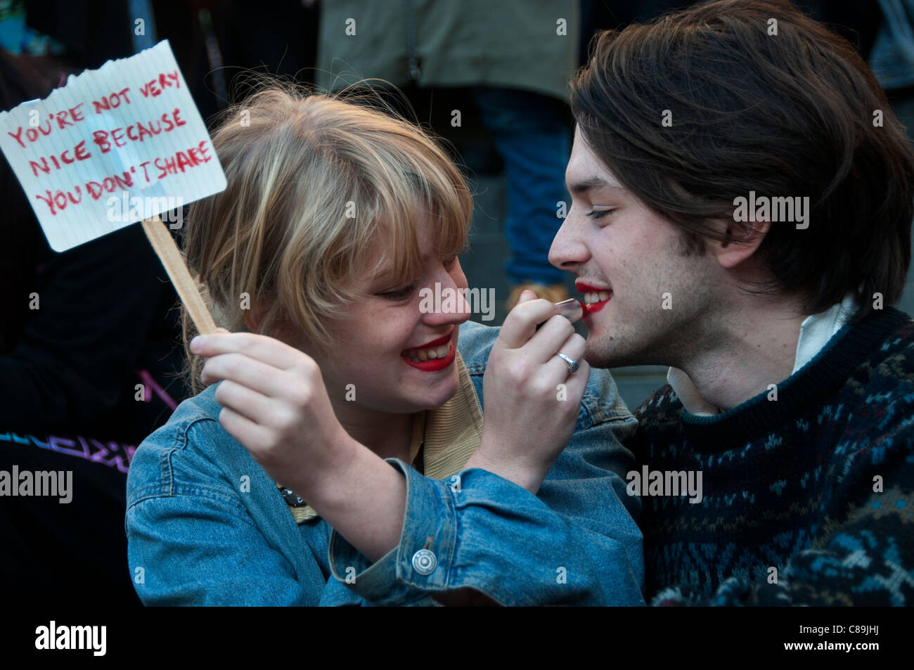 Una ragazza con un piccolo cartello dicendo ' non sei molto bella perché  non si condividono' mette il rossetto sull'uomo che lei è con Foto stock -  Alamy