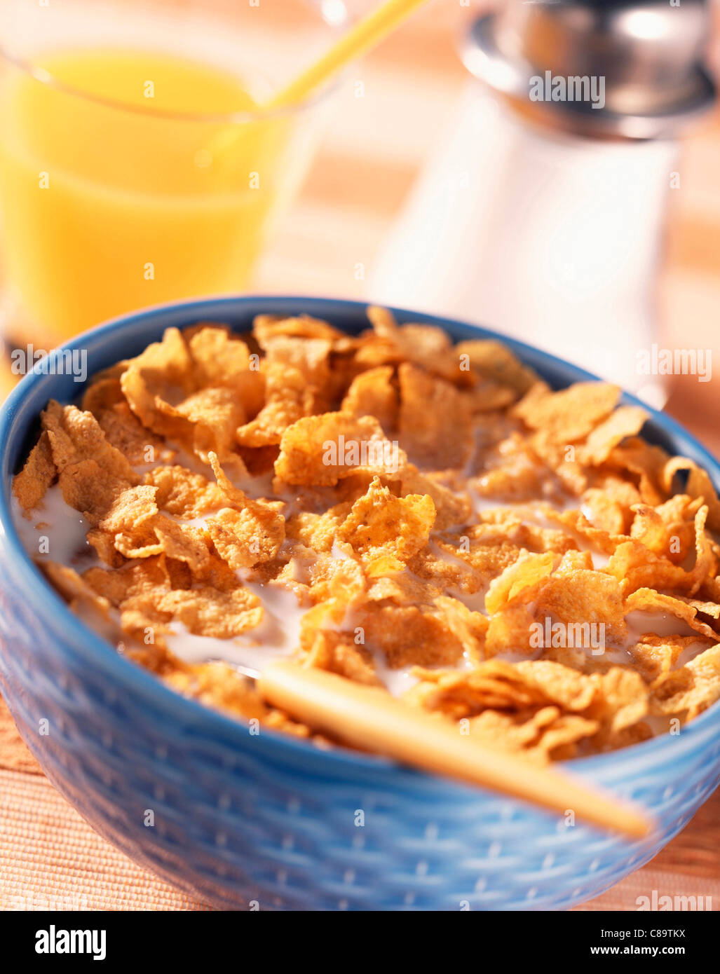 Ciotola di cornflake, latte e bicchiere di succo di arancia Foto Stock