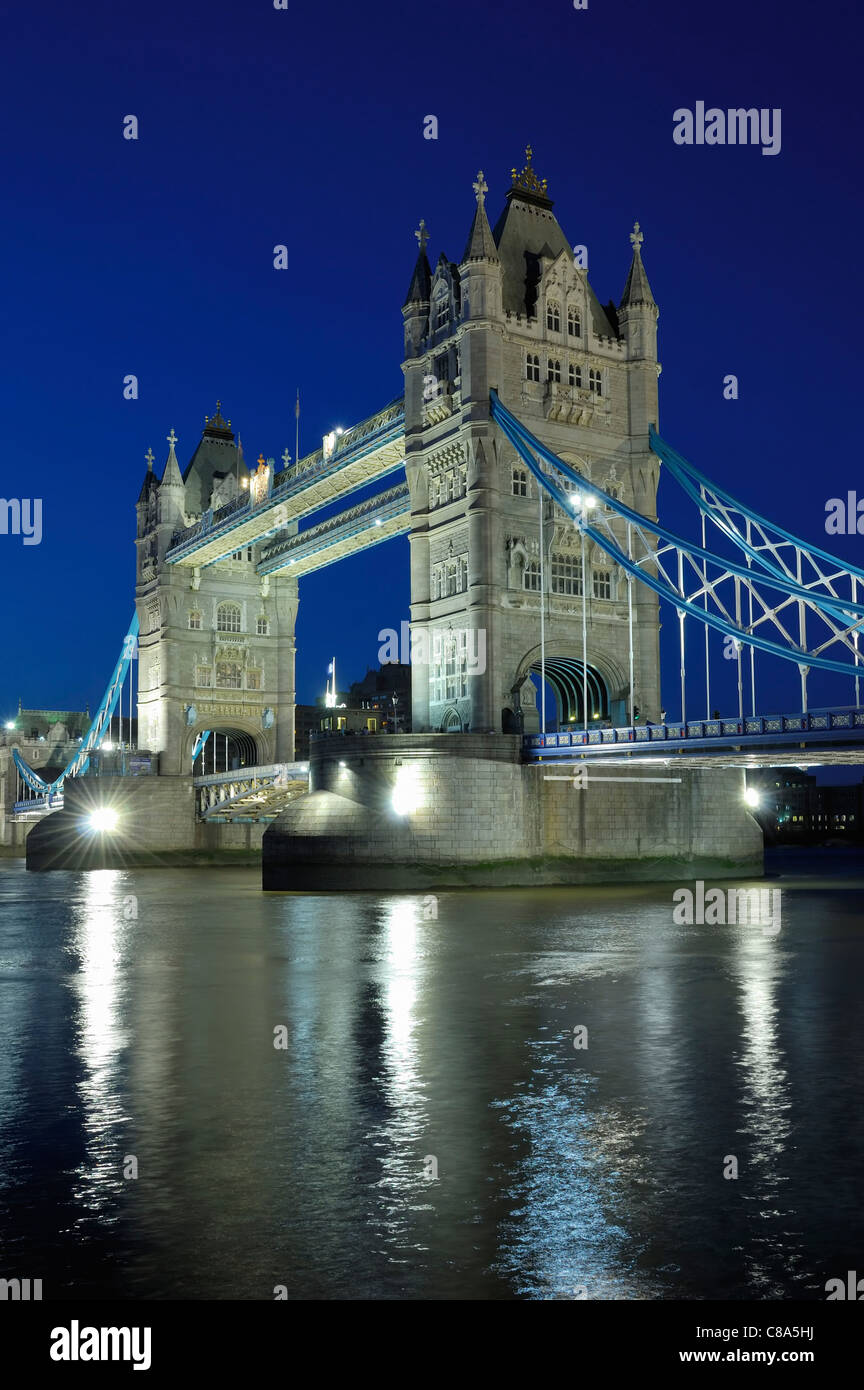 Tower Bridge dalla South Bank del Tamigi, Londra UK, di notte, illuminato, con cielo blu e riflessi nel fiume Foto Stock