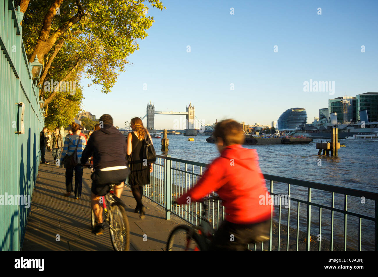 La gente a piedi e in bicicletta lungo il Tamigi il percorso verso il Tower Bridge Foto Stock