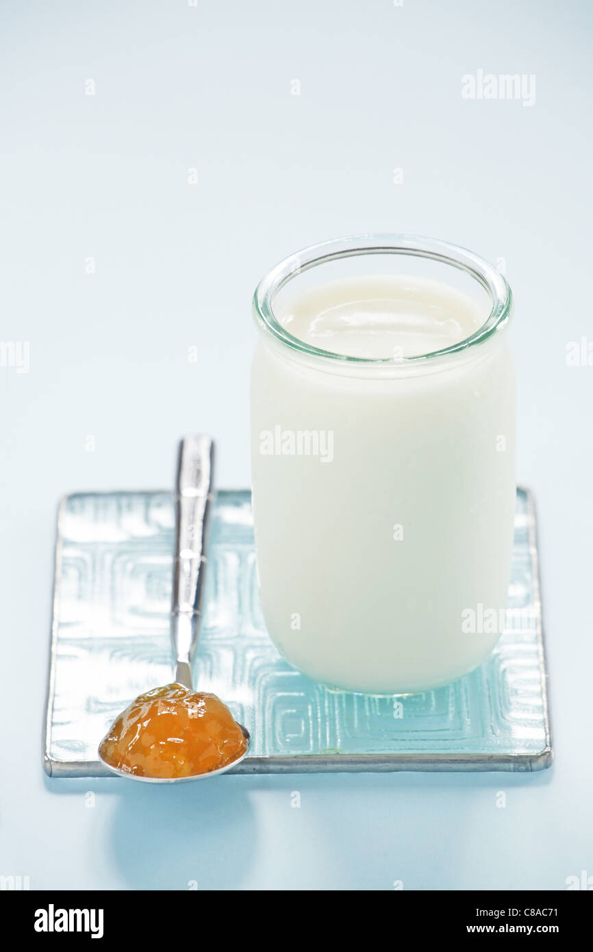 Yogurt naturale in un vaso di vetro e un cucchiaino di marmellata Foto Stock