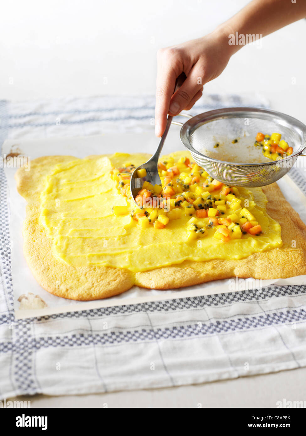 Aggiunta di frutta sul cotto pan di spagna Foto Stock