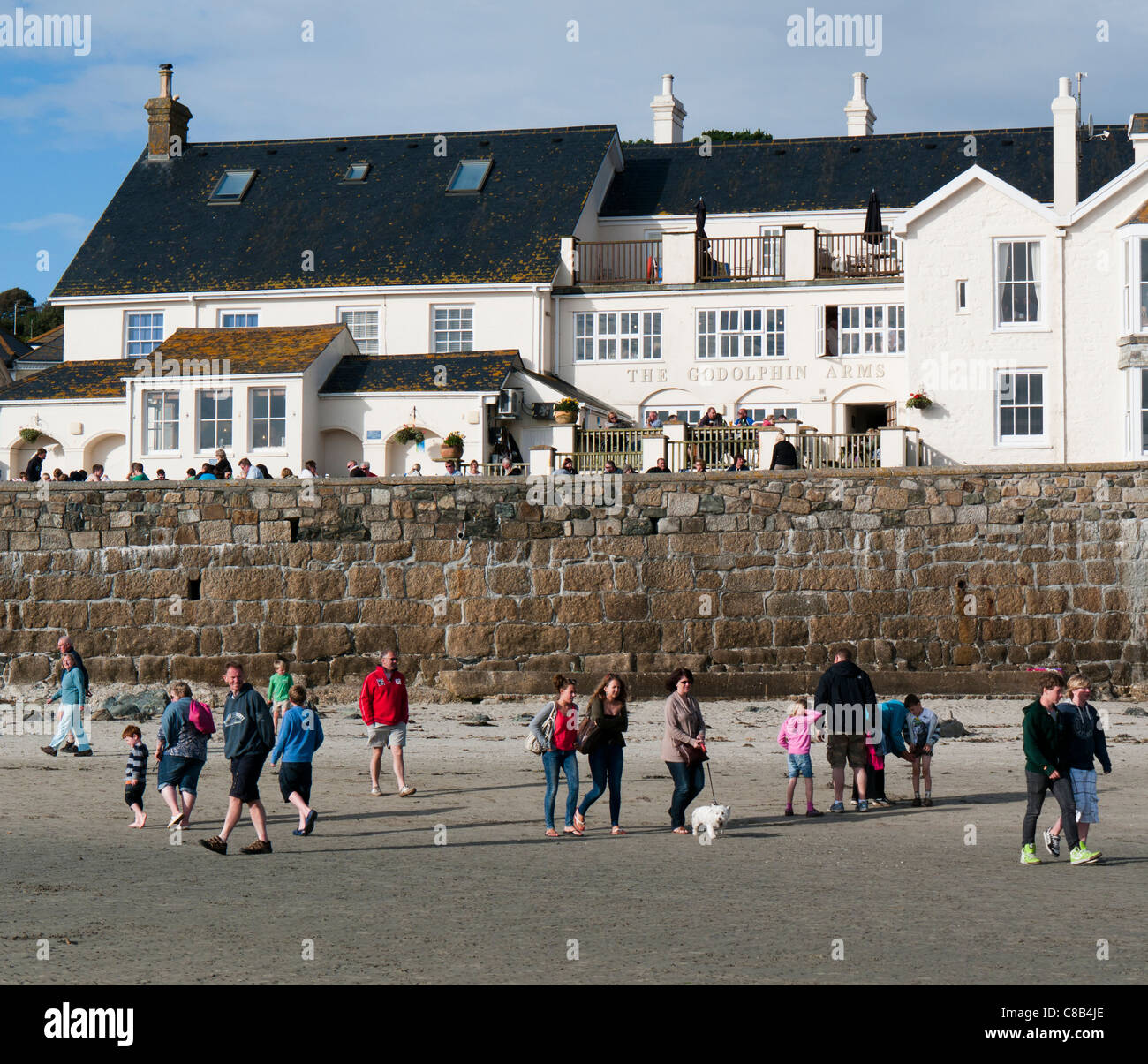 La gente camminare sulla spiaggia di fronte all'Godolphin Arms public house e ristorante in Cornovaglia Gran Bretagna Foto Stock