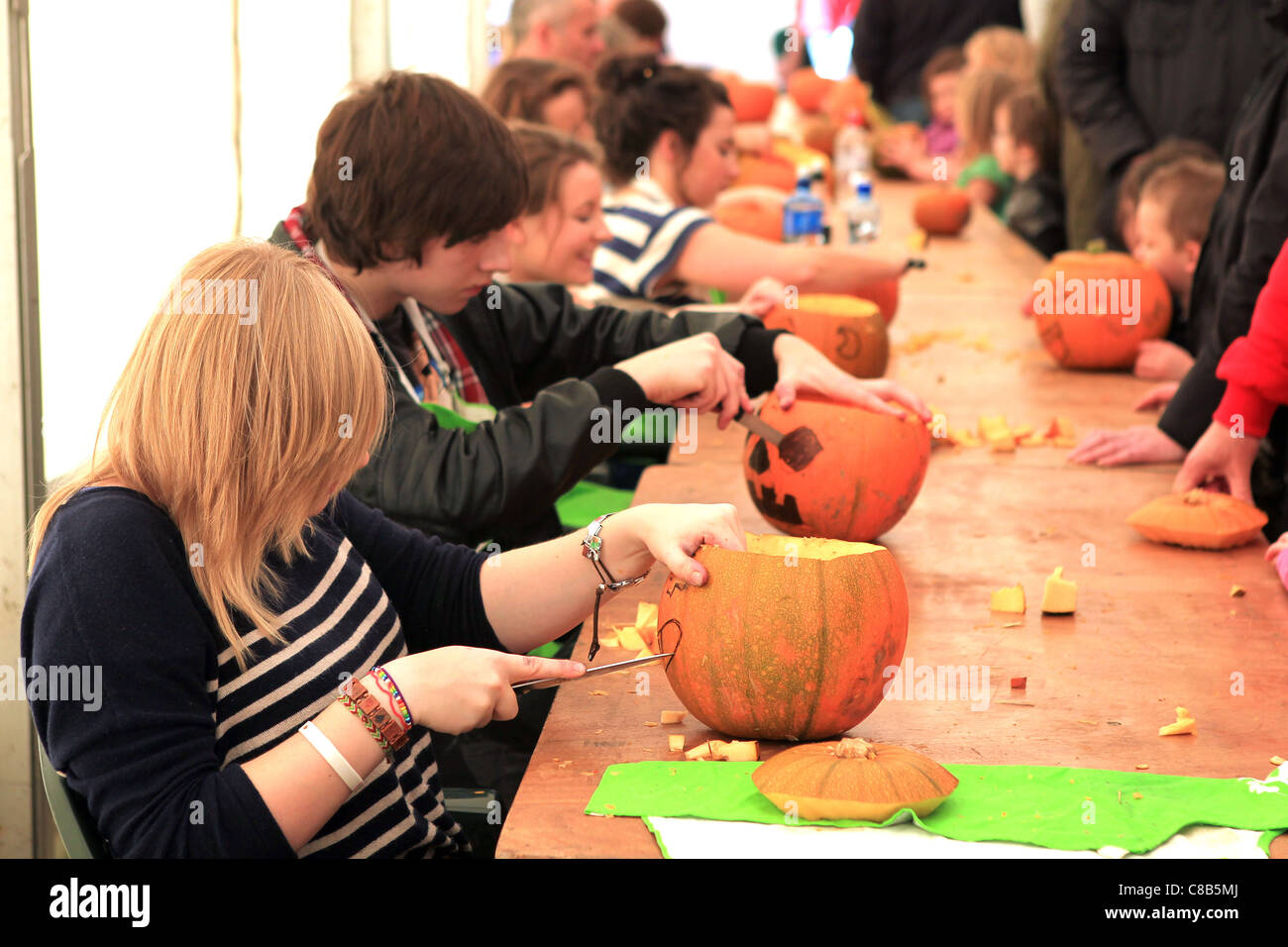 I giovani volontari per intagliare le zucche durante un festival di zucca Foto Stock