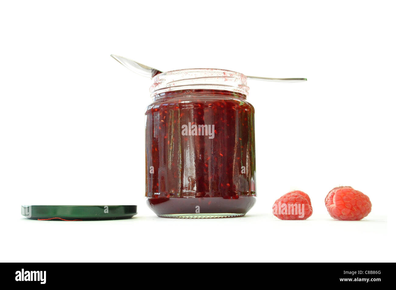 Cucchiaino in appoggio sulla parte superiore di un vasetto di marmellata di lamponi sul lato Foto Stock