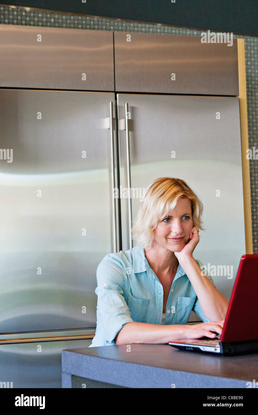 Senior donna con la mano sul mento utilizzando laptop Foto Stock