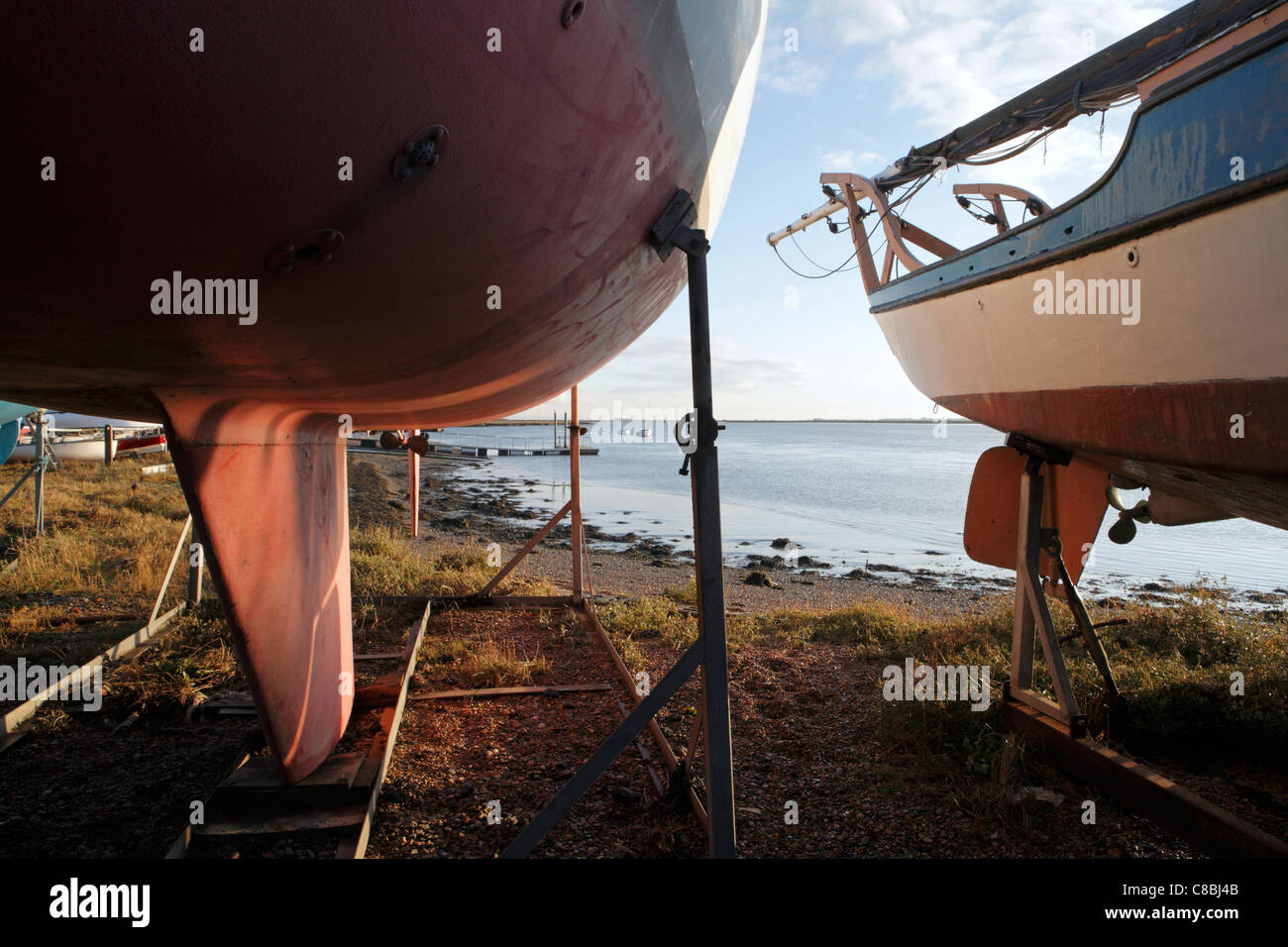 Yachts in basi a terra in cantiere, con River Alde dietro, Aldeburgh, Suffolk Foto Stock
