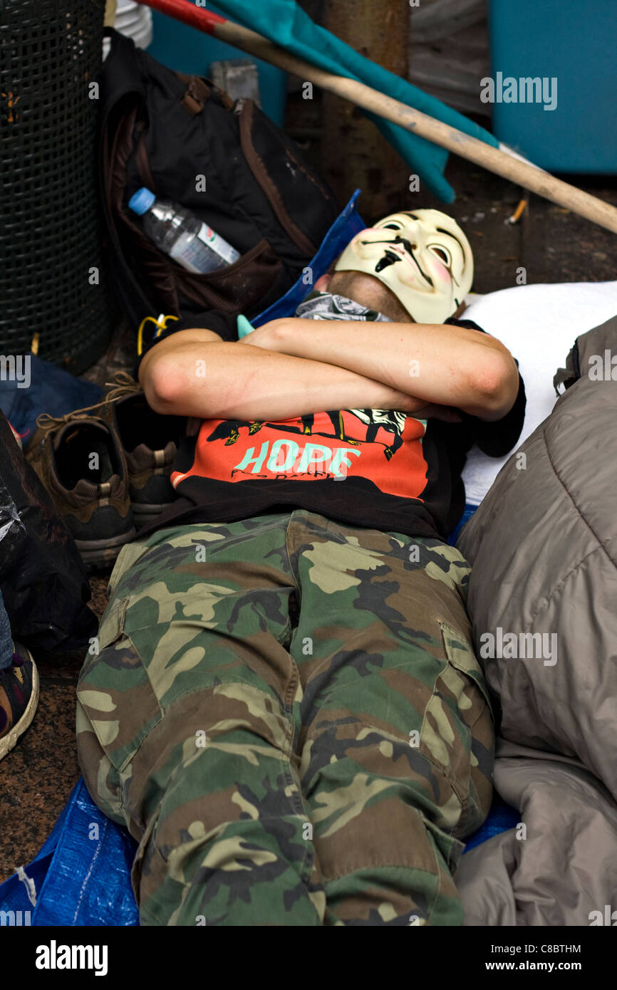 Occupare Wall Street protester indossando maschera di Guy Fawkes dorme in Zuccotti Park dopo una notte di tesa di pulizia per evitare sfratti. Foto Stock
