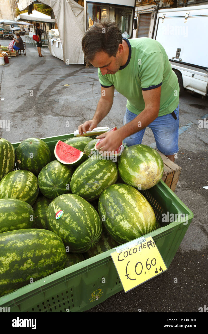 Un venditore di frutta prepara il melone di acqua alla strada del mercato di Sulmona, Italia. Foto Stock