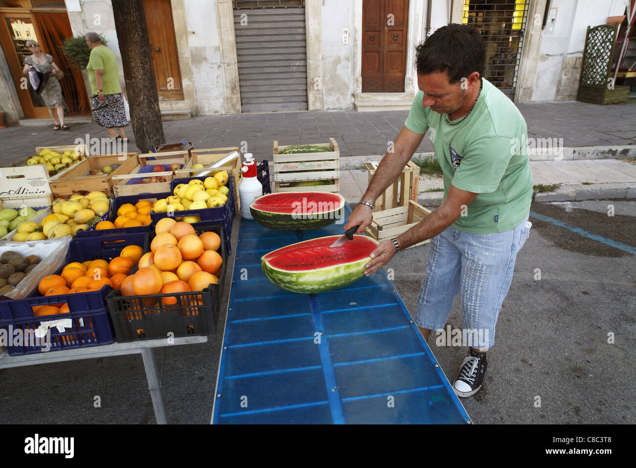 Un commerciante prepara il melone di acqua alla strada del mercato di Sulmona, Italia. Foto Stock