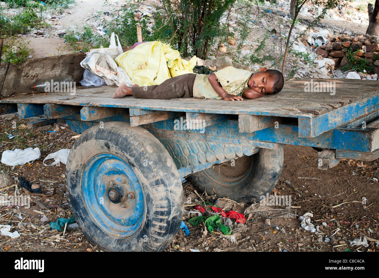 I giovani poveri di casta inferiore Indian street boy dormire su di un carrello di giovenco sulla massa di rifiuti. Andhra Pradesh, India Foto Stock