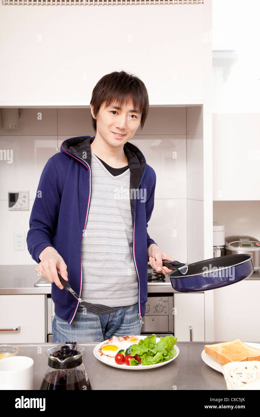 Giovane uomo cooking per colazione Foto Stock