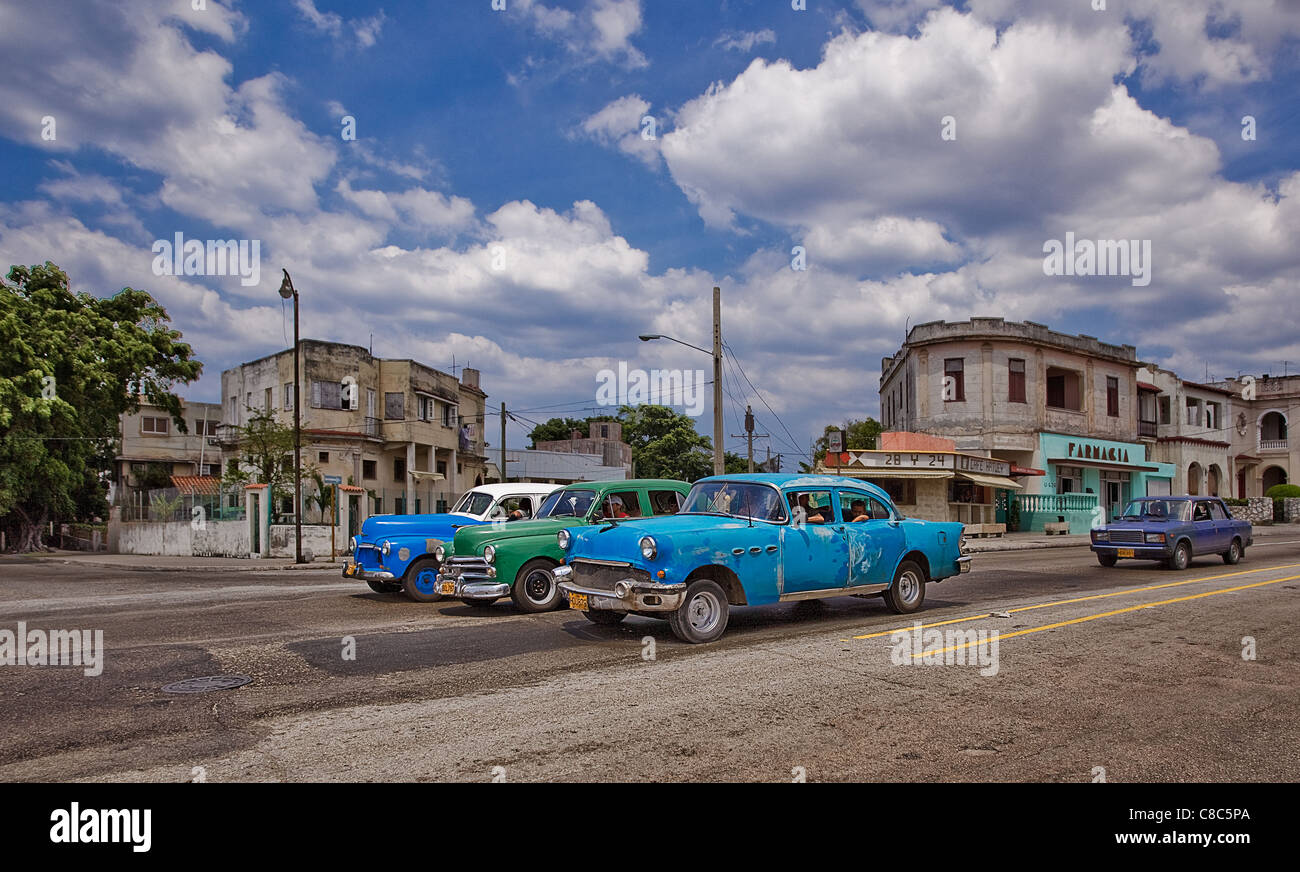 3 vecchie automobili sulle strade di La Havana e som case usurati Foto Stock