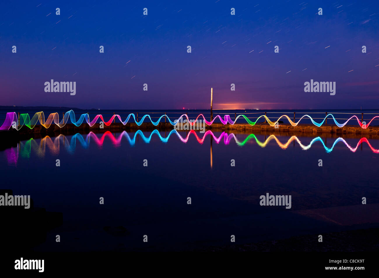 Dimostrazione di pittura di luce usando un bastone di luce presso le piscine di balneazione, St Peter Port Guernsey, Isole del Canale, REGNO UNITO Foto Stock